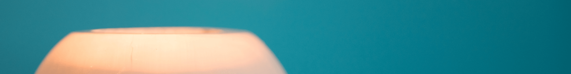 teal background with a white candle holder in the right hand side.